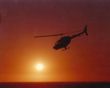 Bell 206B-1 helicopter flying off into the sunset.