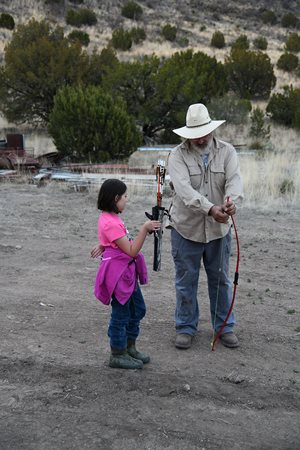Grandpa teaching his granddaughter about archery